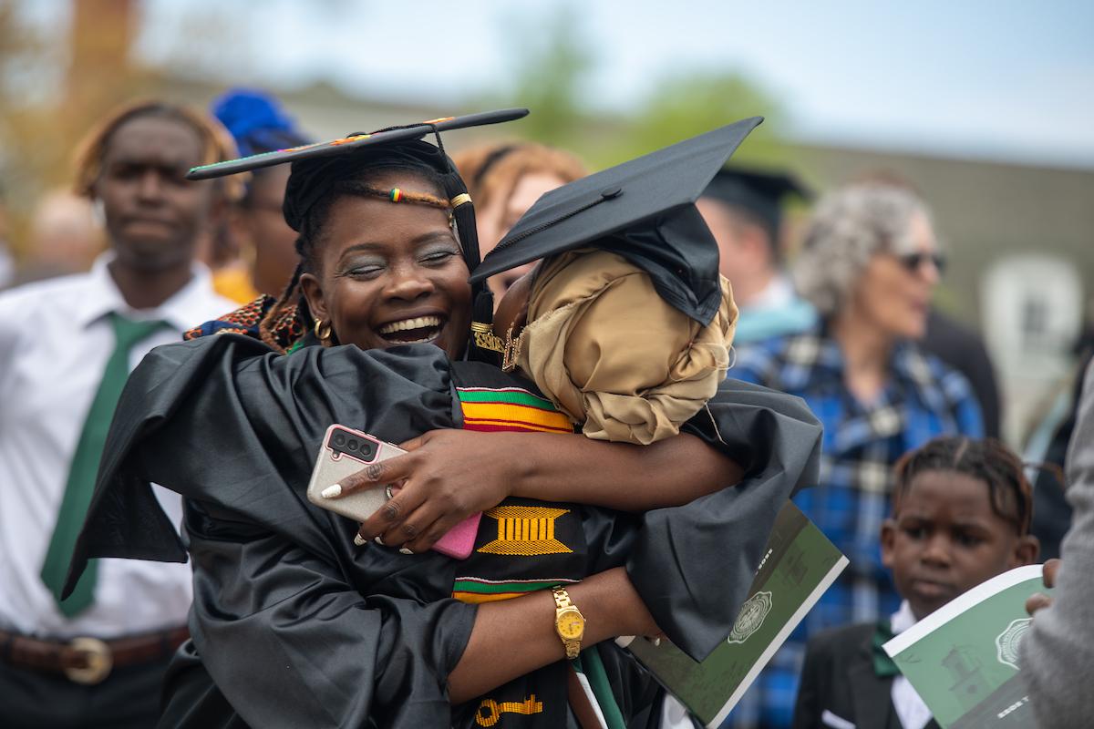 Two graduate students hug and celebrate after graduating